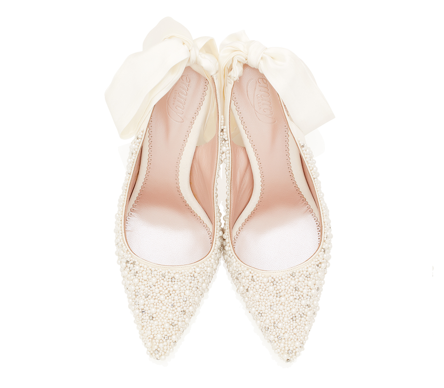Elegant ivory heels adorned with intricate pearl detailing, featuring a pointed toe design. The shoes are complemented by a delicate bow at the back, enhancing their sophisticated look. The image is taken from a top-down angle against a clean, white background, showcasing the shoes in pristine condition. image