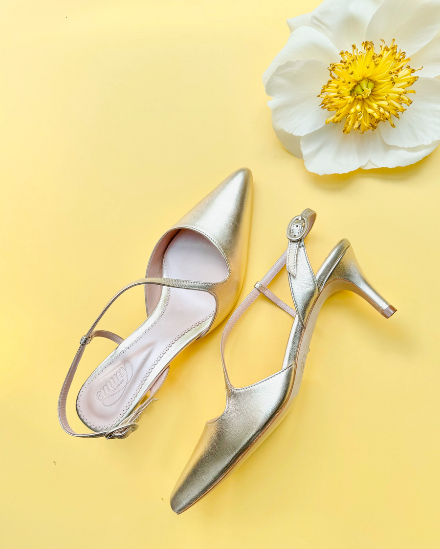 Gold low-heeled shoes with a white flower on a yellow background image