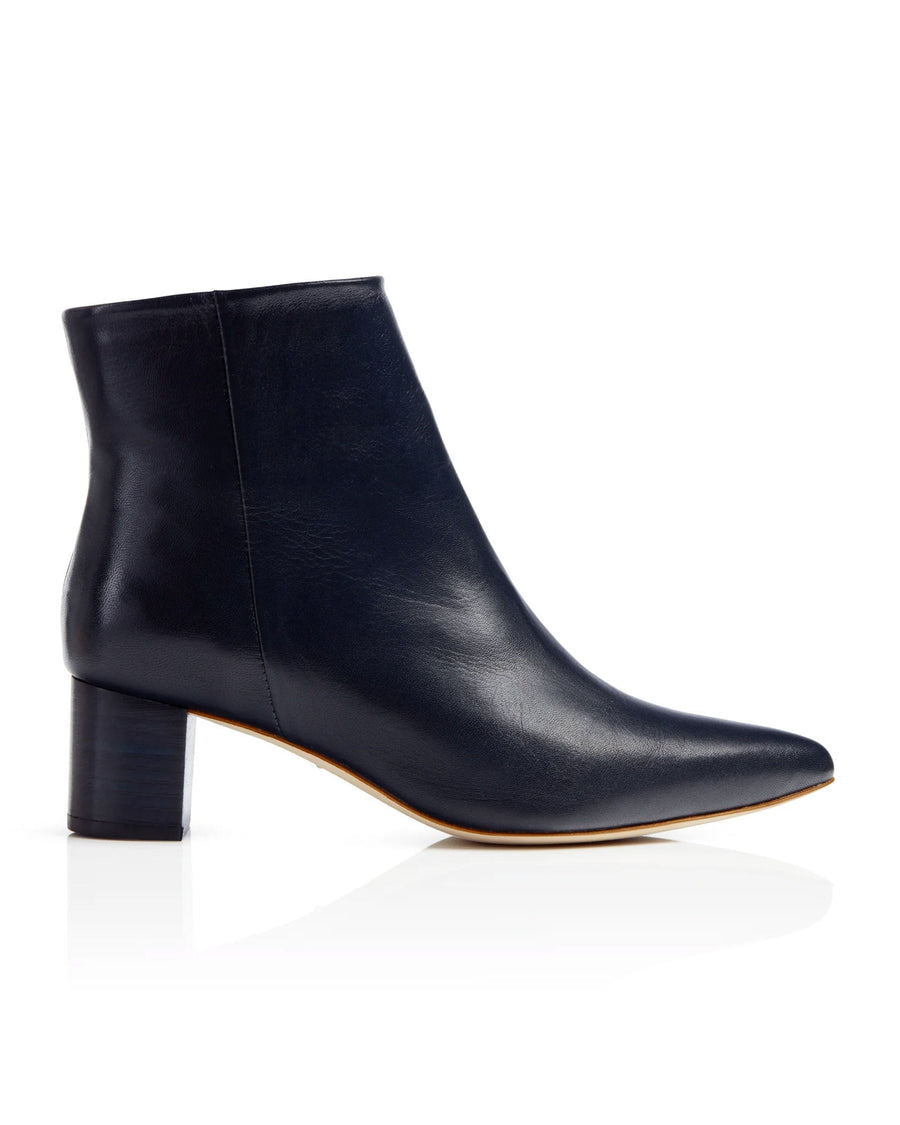 Navy leather ankle boots with a block heel, featuring a pointed toe design. The image is taken from a side angle, showcasing the smooth finish of the leather. The background is a clean, white surface, emphasizing the sleek silhouette of the boots. image