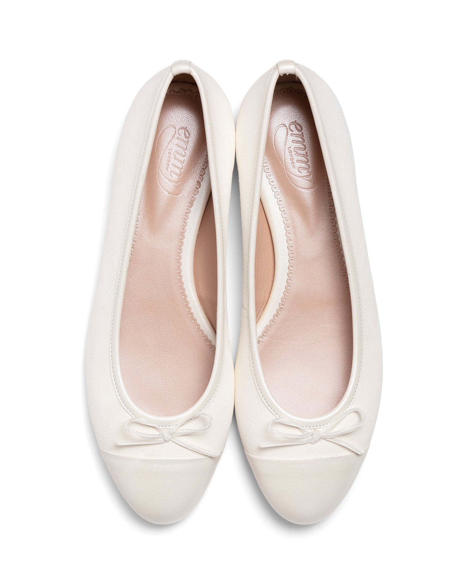 Pair of white ballet flats with bow details on a white background image