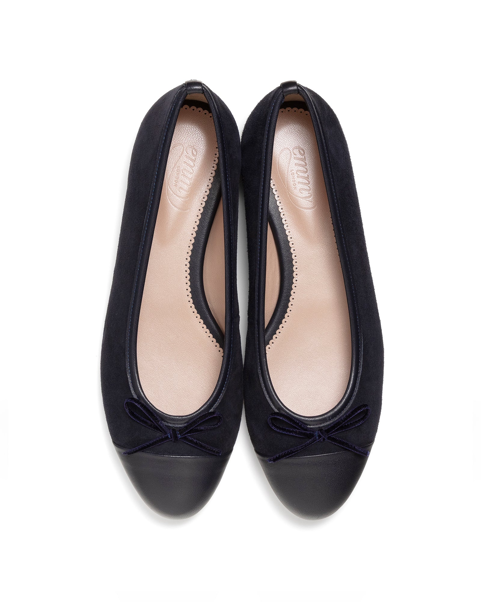 Pair of navy ballerina shoes with bow detail on a white background image