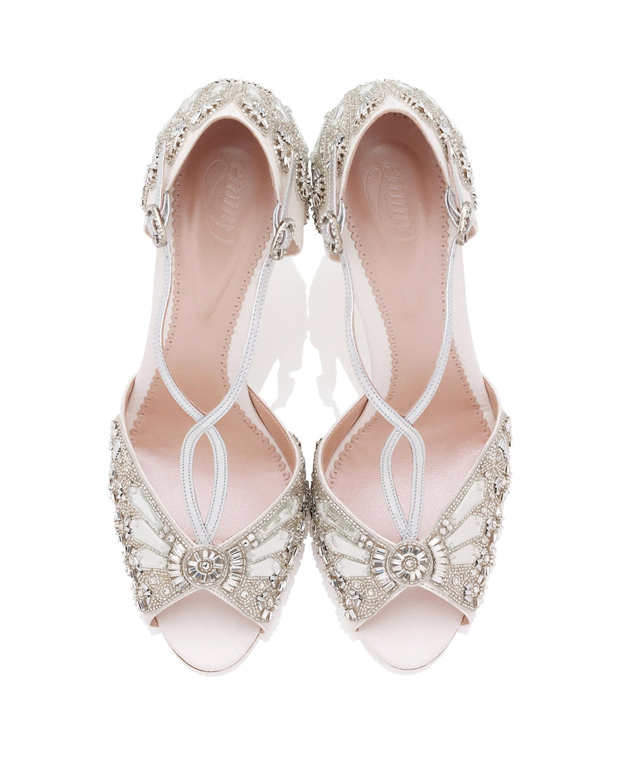 Elegant open-toe heels featuring intricate beading and embellishments. The shoes are predominantly white with silver accents, showcasing a delicate design. The image is taken from a top-down angle, highlighting the detailed craftsmanship. The background is plain white, emphasizing the shoes' ornate features. image