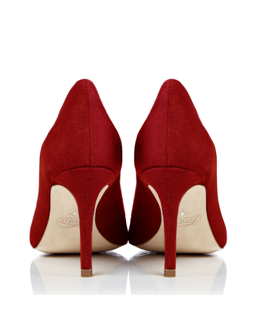 Red suede heels with a pointed toe design, featuring a stiletto heel. The image captures the shoes from the back, showcasing their sleek silhouette against a clean, white background. image