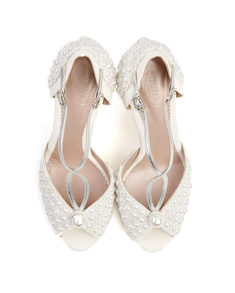 Elegant white shoes adorned with pearls and silver accents, featuring a delicate strap design. The shoes are displayed from a top-down angle against a clean white background, showcasing their intricate detailing. image