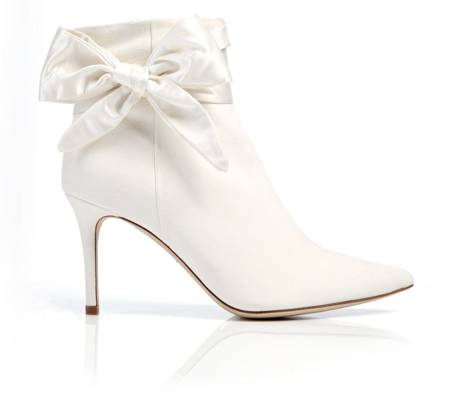 White ankle boots with a pointed toe and a satin bow detail at the ankle. The heels are stiletto-style, showcasing a sleek silhouette. The image is taken against a clean, white background, highlighting the elegant design of the boots. image