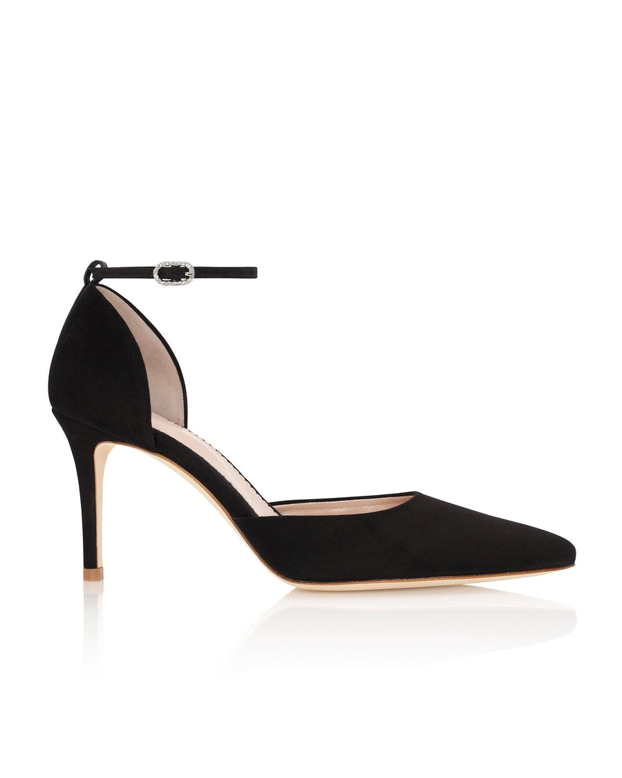 Black suede heels with a pointed toe and an ankle strap, set against a white background. The shoe features a slim stiletto heel, showcasing a sleek and elegant design. image