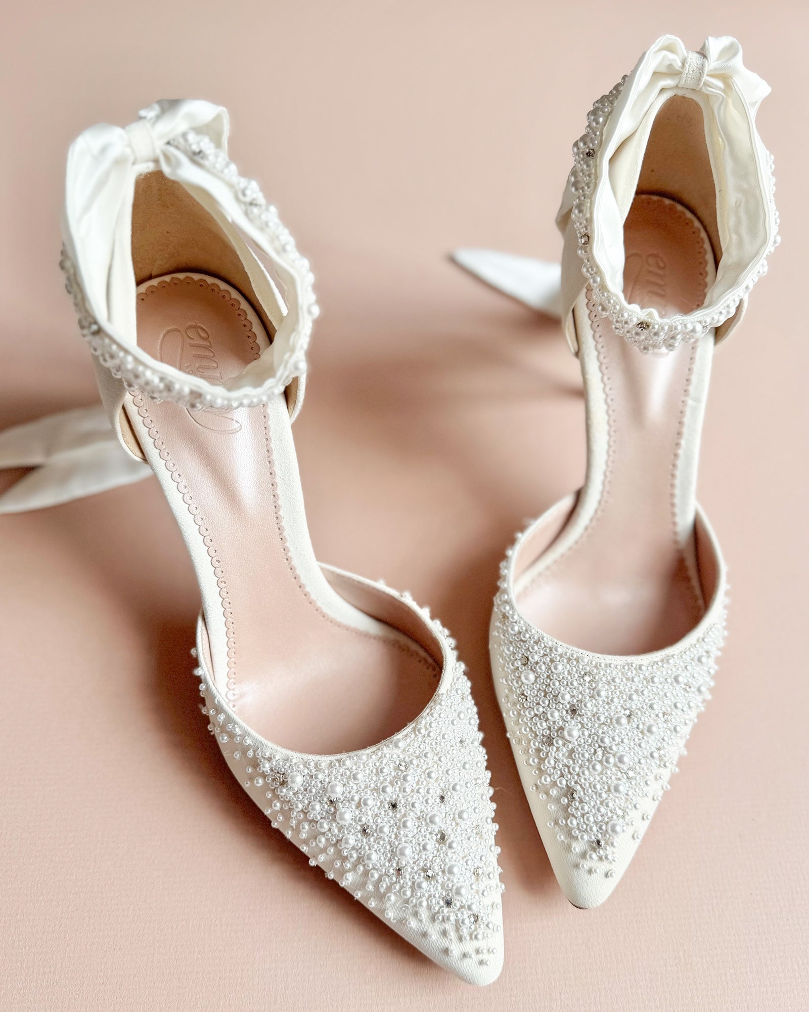 White beaded bridal shoes on pink background image