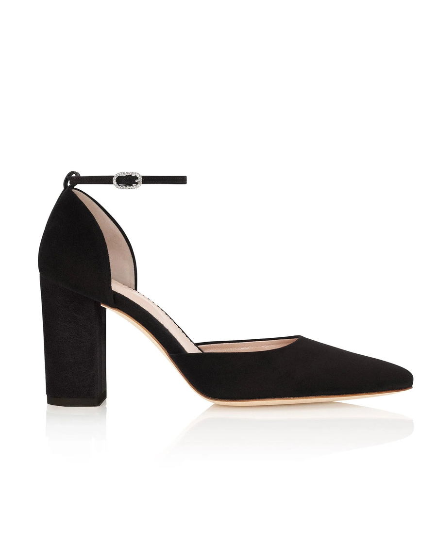 Black suede high-heeled shoe with a pointed toe and a chunky heel. The shoe features an ankle strap with a decorative buckle. The image is taken from a side angle, showcasing the shoe against a neutral background. image
