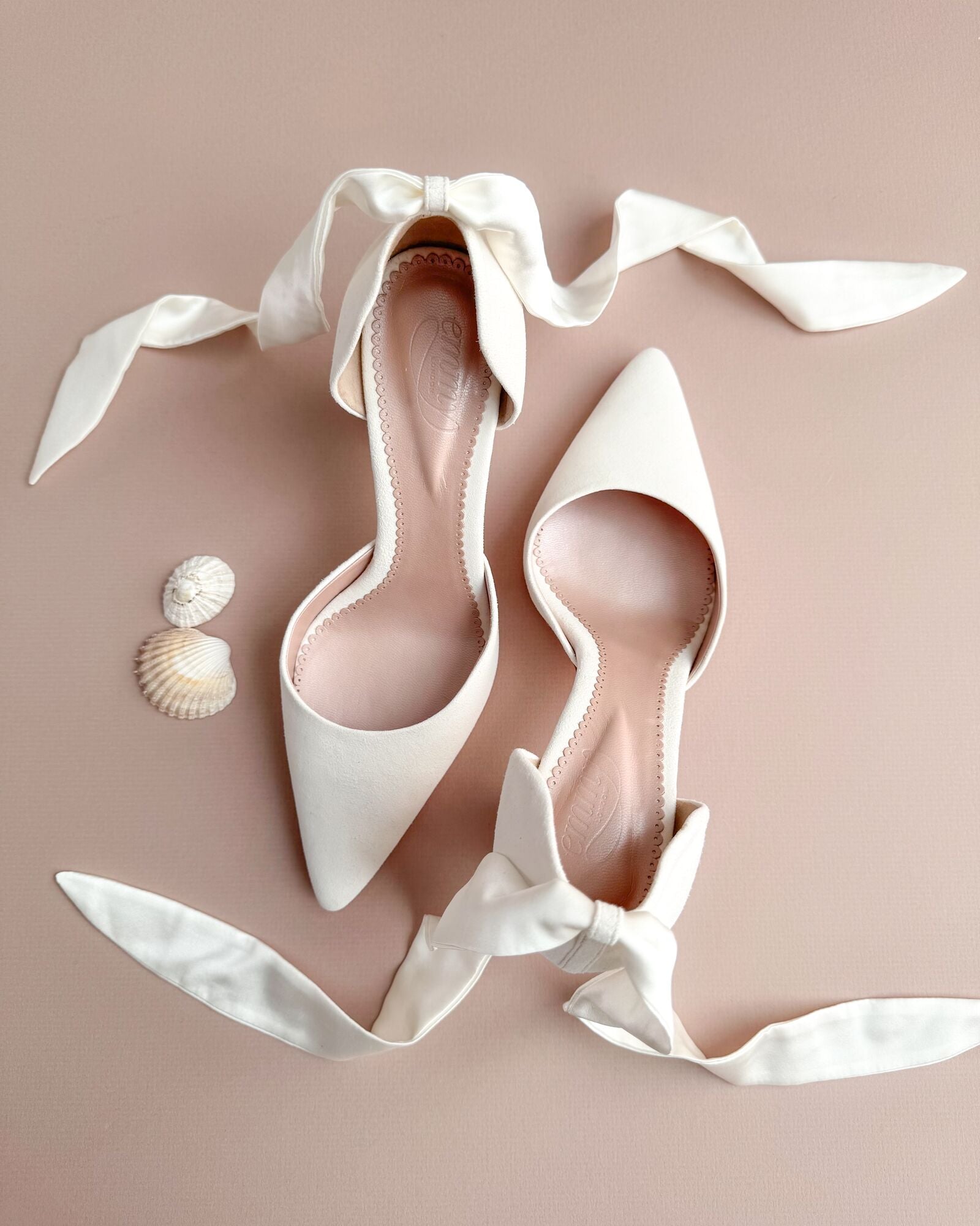 White high-heeled shoes with ribbons on a beige background image