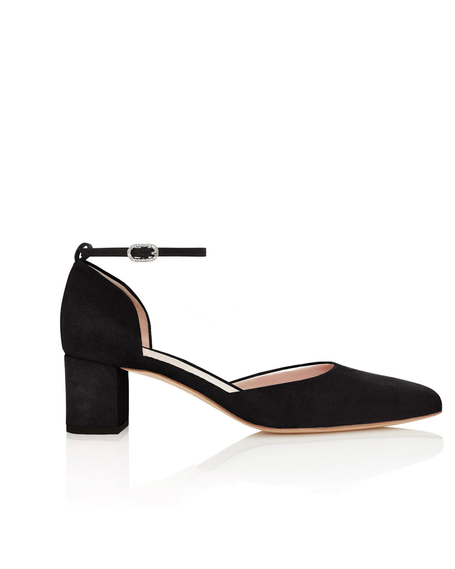 Black suede block-heeled shoes with a pointed toe and an ankle strap. The image is taken from a side angle, showcasing the shoe's sleek design and the smooth finish of the suede material. The background is a clean, white surface, emphasizing the shoe's elegant silhouette. image