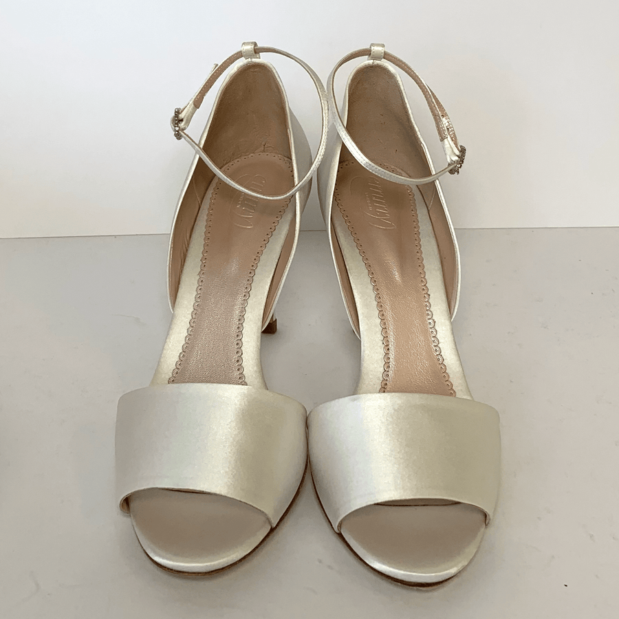 Elegant open-toe heels in a soft ivory satin finish, featuring a wide front strap and a delicate ankle strap for added support. The shoes are displayed against a plain white background, showcasing their sleek design from a top-down angle. The heel height is approximately 2 inches, providing a comfortable yet stylish lift. image