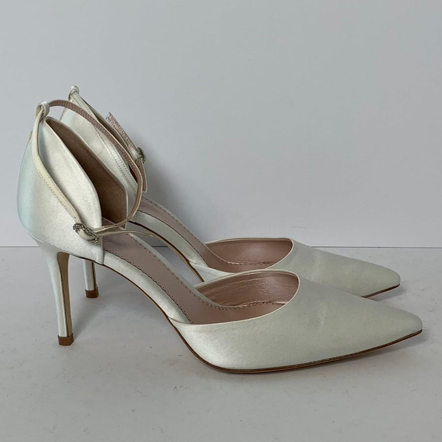 Elegant white heels with a pointed toe and a delicate ankle strap. The shoes are positioned side by side against a plain white background, showcasing their sleek design and stiletto heel. The heel height is approximately 4 inches. image
