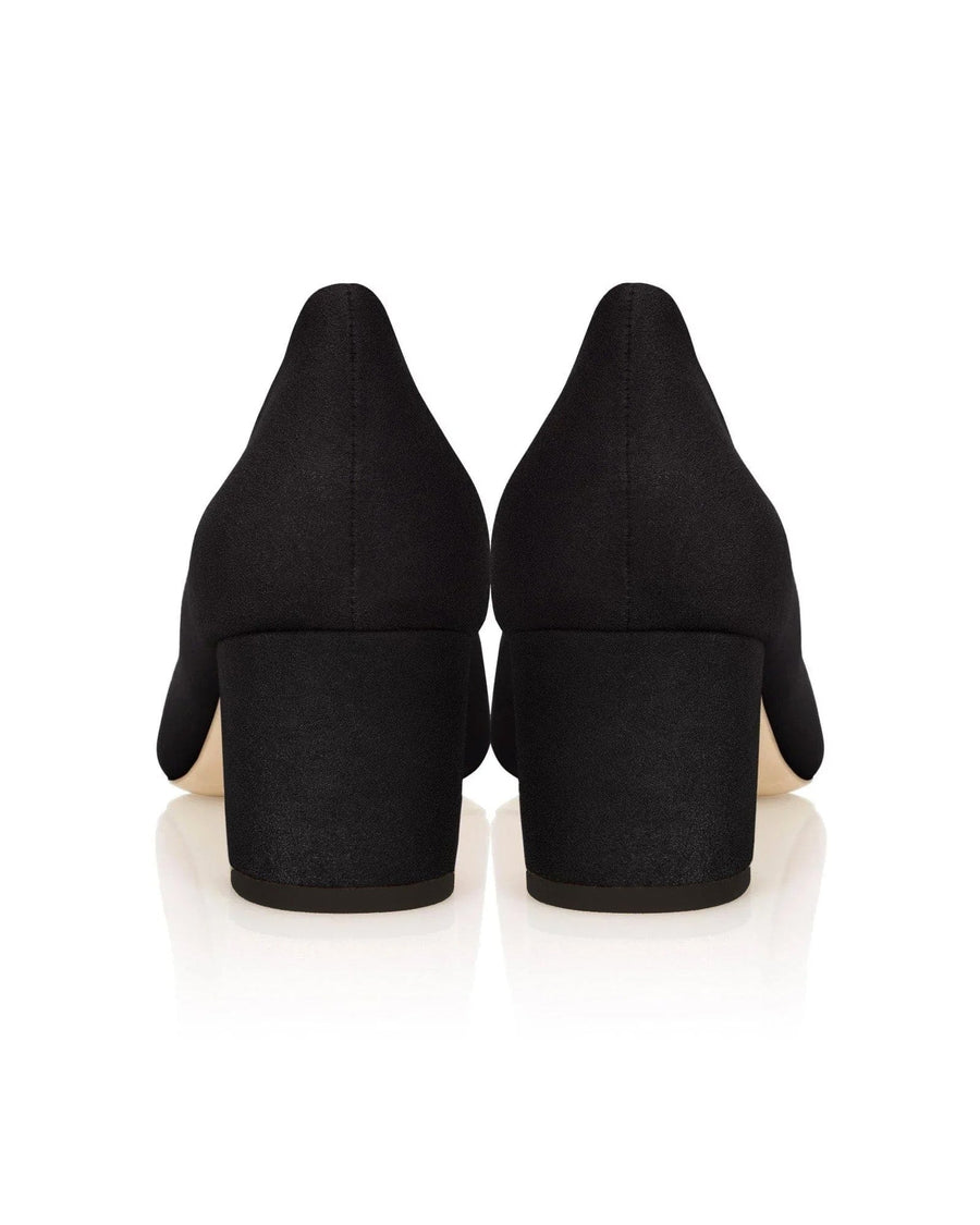 Black suede heels with a block heel design, featuring a smooth finish. The image shows the back view of the shoes against a reflective white background, highlighting their sleek silhouette. image