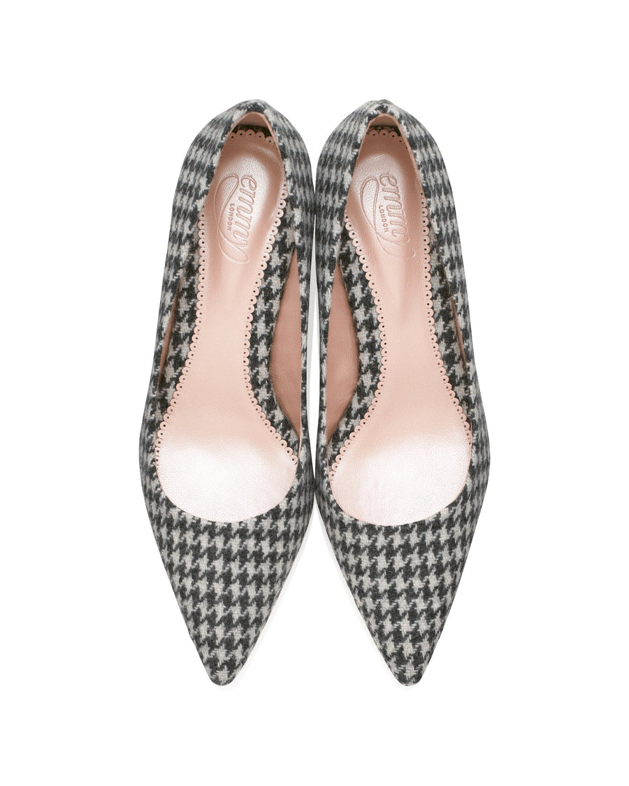 Pointed-toe heels made of tweed, featuring a classic houndstooth pattern in black and white. The shoes are displayed from a top-down angle against a clean, white background, showcasing their elegant silhouette and interior lining. image