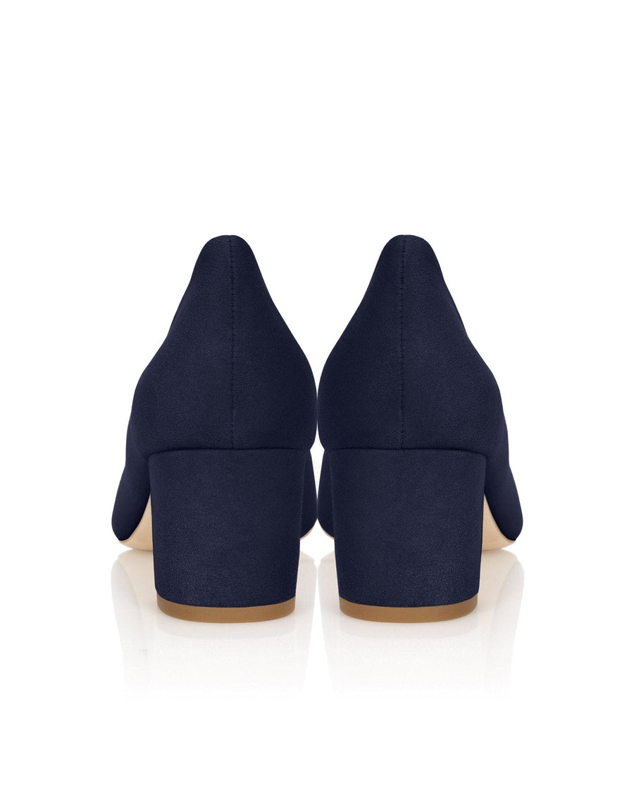 Navy blue suede heels with a block heel design, featuring a smooth finish. The image shows the back view of the shoes against a reflective white background, highlighting their elegant silhouette. image