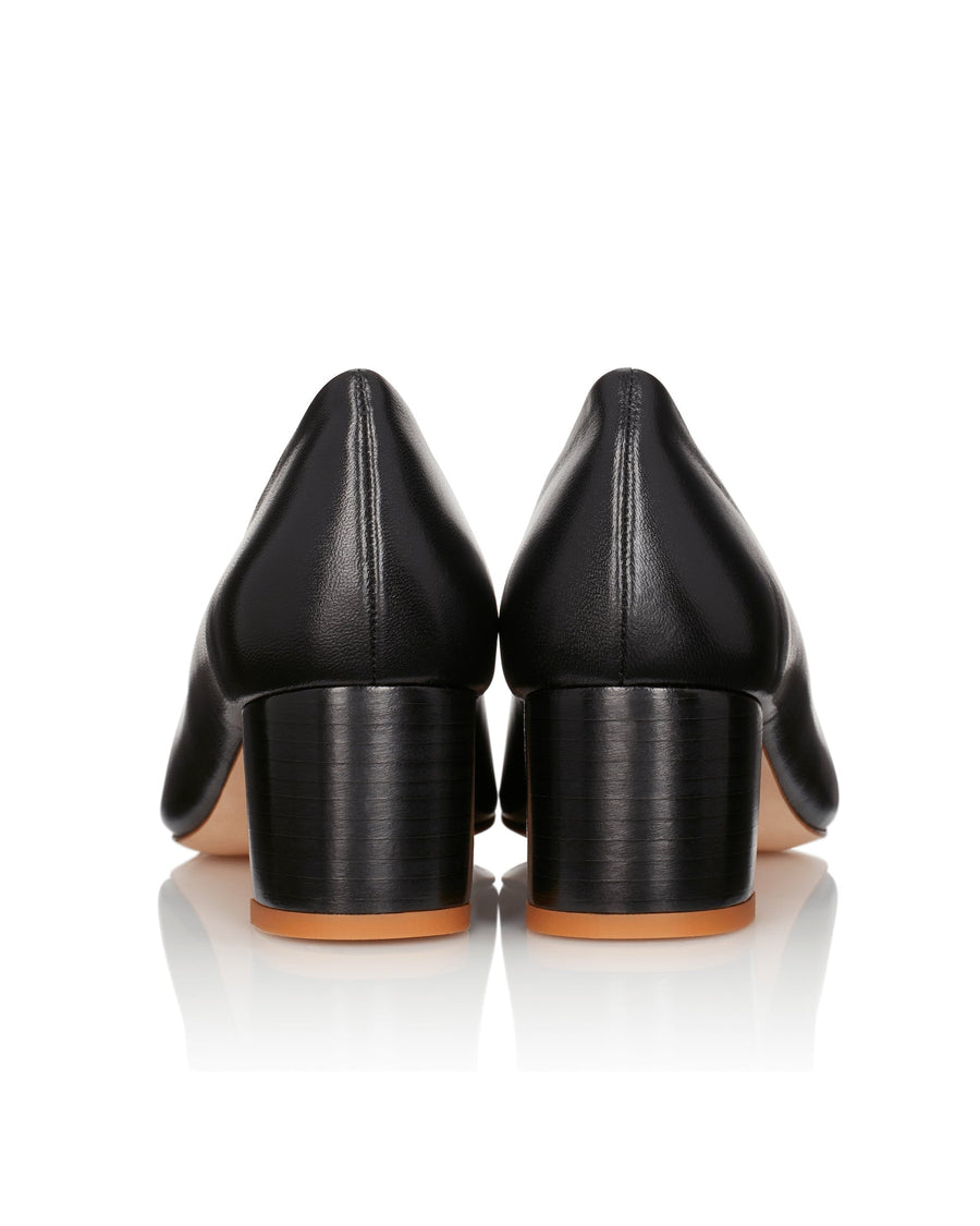 Black leather heels with a block heel design, featuring a smooth finish. The image is taken from the back, showcasing the rounded toe and the sturdy heel. The background is a clean, reflective surface that highlights the shoes. image