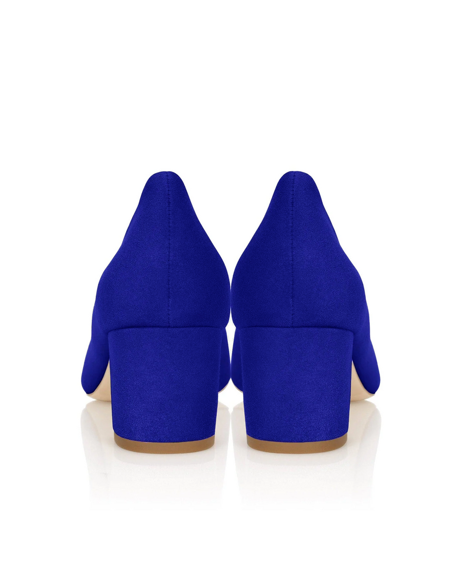 Blue suede heels with a block heel design, featuring a smooth finish. The image shows the back view of the shoes against a reflective white background, highlighting their vibrant color and clean lines. image