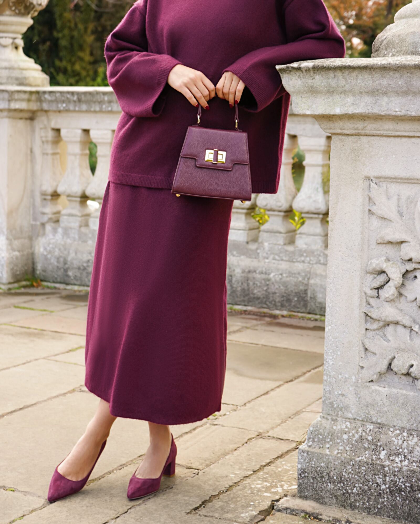 Woman in a purple outfit holding a matching handbag outdoors. image