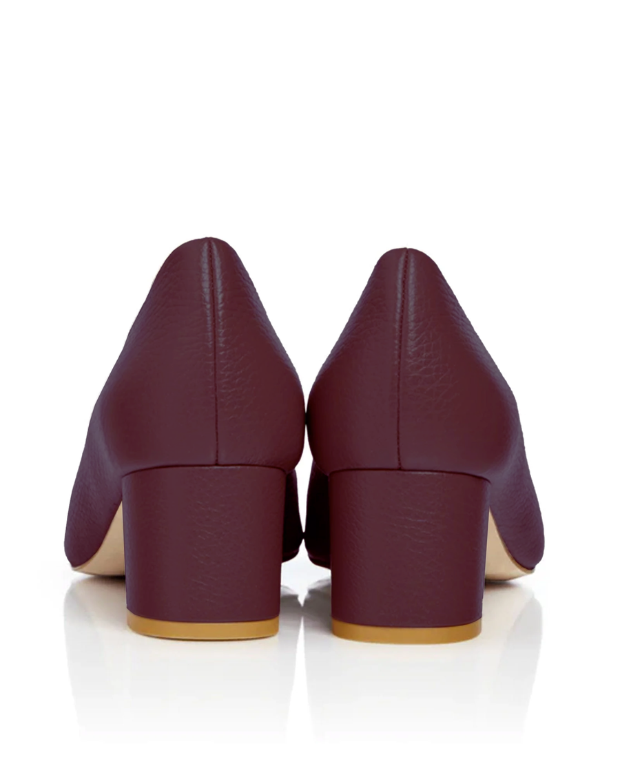 Block-heeled shoes in a rich burgundy color, featuring a textured leather finish. The image shows the back view of the shoes, highlighting the sturdy block heel. The background is a clean, white surface, emphasizing the shoe's design. image