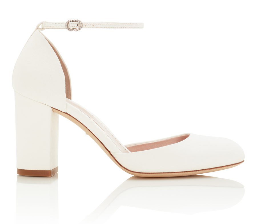 White block-heeled shoes with a rounded toe and ankle strap, set against a clean white background. The heel is approximately 3.5 inches high, made of leather. The shoe is displayed from a side angle, showcasing its elegant design. image