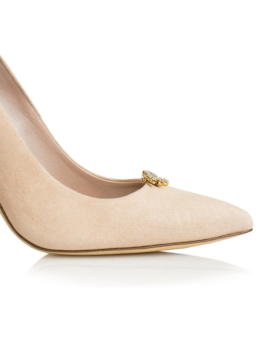 Nude suede pump with a pointed toe and a decorative gold embellishment on the vamp. The shoe is positioned at an angle against a white background, showcasing its sleek silhouette. image
