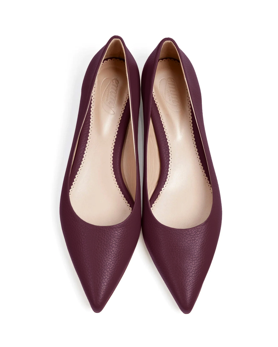 Elegant pointed-toe flats in a rich burgundy color, crafted from smooth leather. The shoes feature a sleek design with a low-cut vamp, showcasing a minimalist aesthetic. The image is taken from a top-down angle against a clean white background, highlighting the shoes' refined silhouette. image