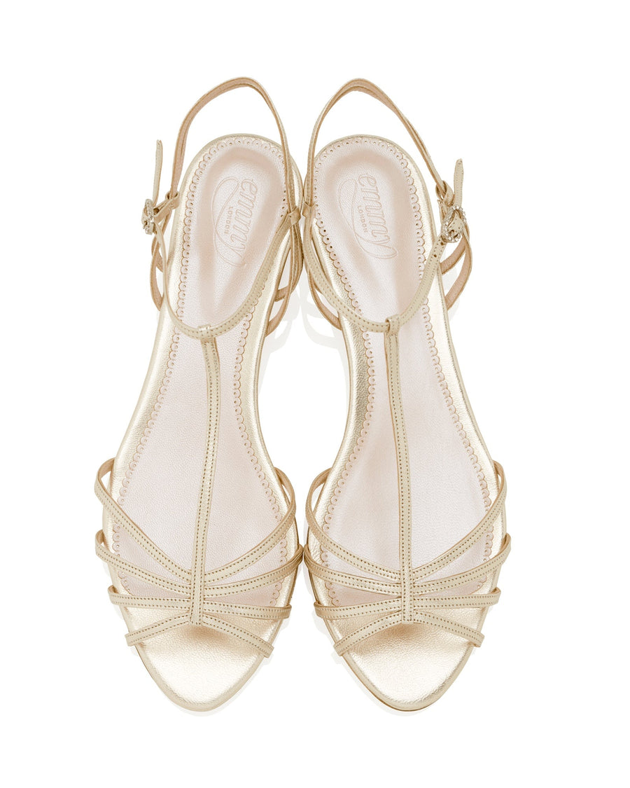 Strappy sandals in a light beige color with a flat heel. The shoes feature multiple thin straps across the foot and an adjustable ankle strap. The image is taken from a top-down angle against a white background, showcasing the intricate design of the straps. image