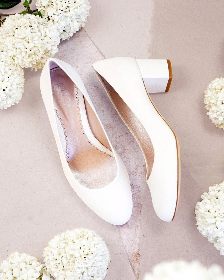 White high-heeled shoes on a light pink background with white flowers. image