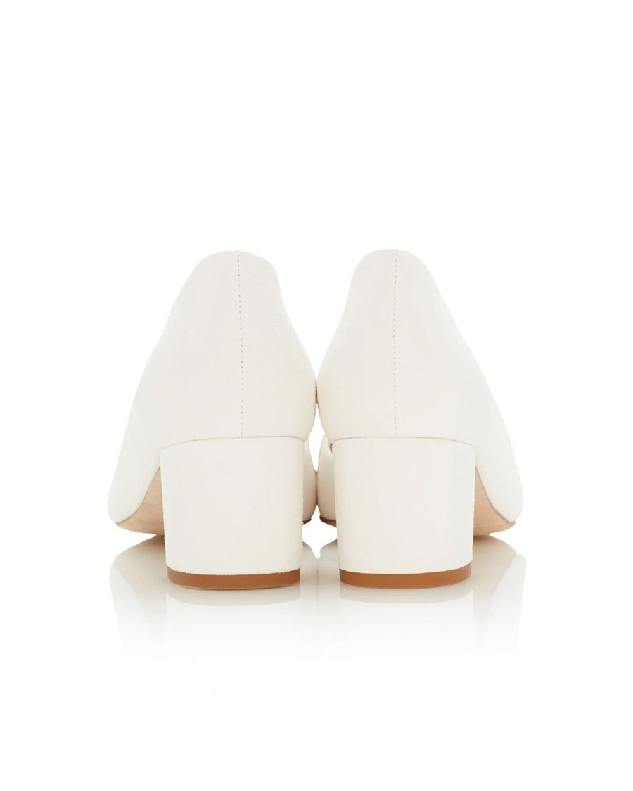 White block-heeled shoes with a smooth finish, featuring a rounded toe and a mid-height heel. The shoes are positioned against a reflective white background, showcasing their clean lines and elegant design. The angle captures the back view, highlighting the heel structure. image