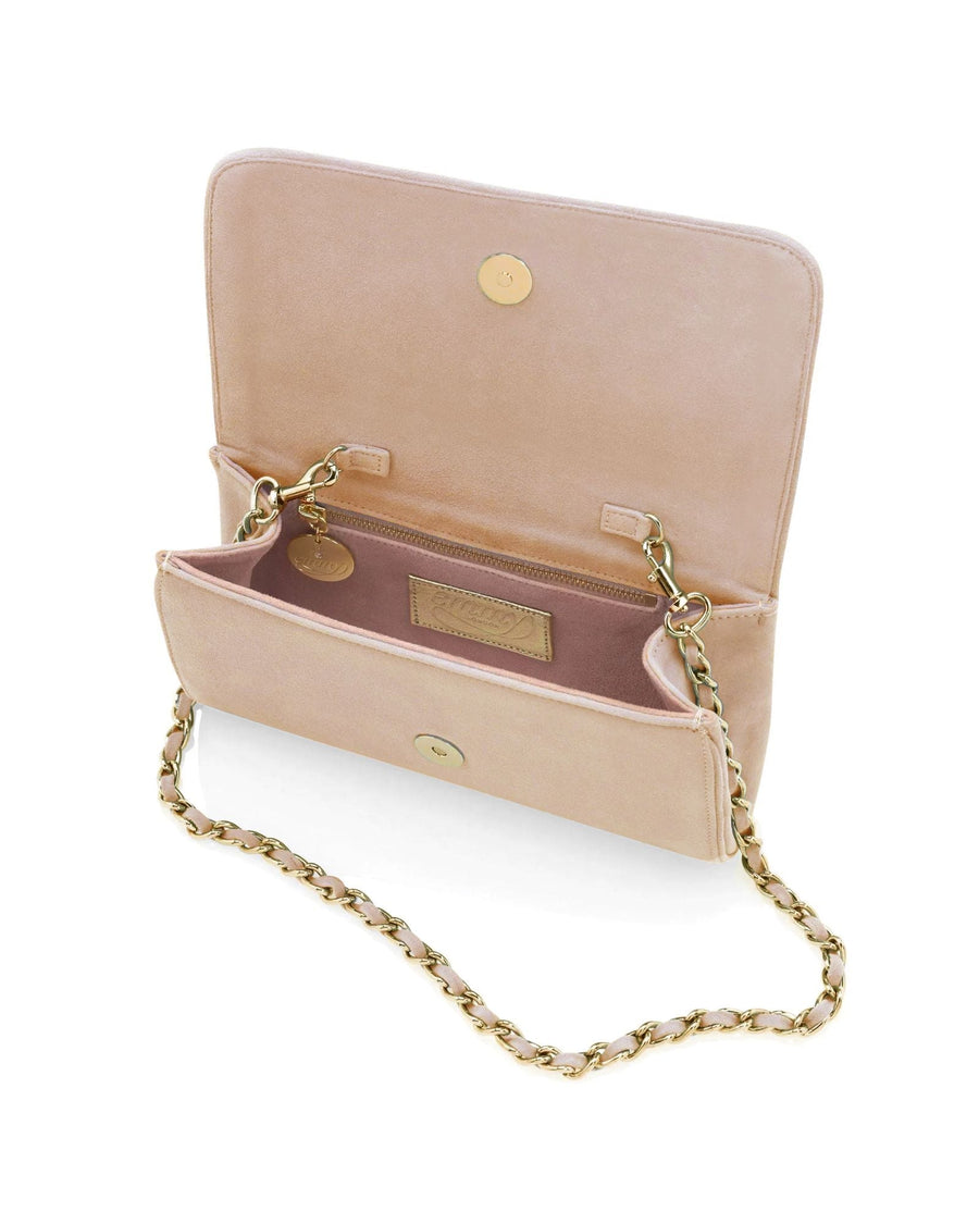 This image features a light pink suede handbag with a gold chain strap. The bag is open, showcasing its spacious interior, which includes a small pocket and a tag. The background is plain white, emphasizing the bag's design and color. image