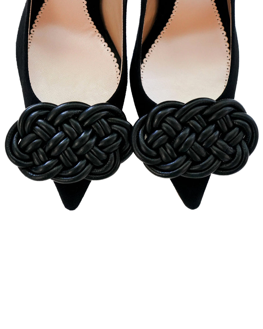 Black suede pointed-toe shoes featuring a large woven black embellishment at the front. The shoes are displayed from a top-down angle against a neutral background, highlighting the intricate detailing of the embellishment. image