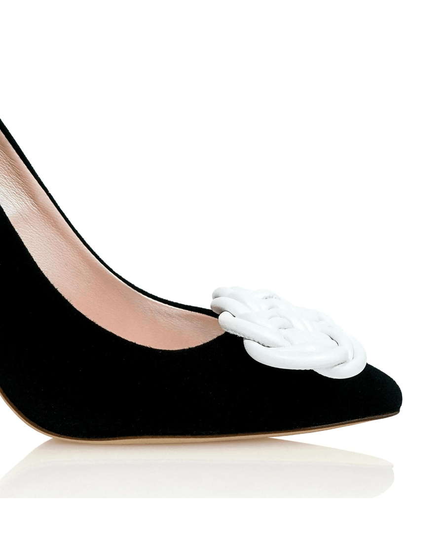 Black suede pump with a pointed toe and a white braided detail on the front. The shoe is shown from a side angle, highlighting the sleek silhouette and elegant design. The background is plain white, emphasizing the shoe's features. image