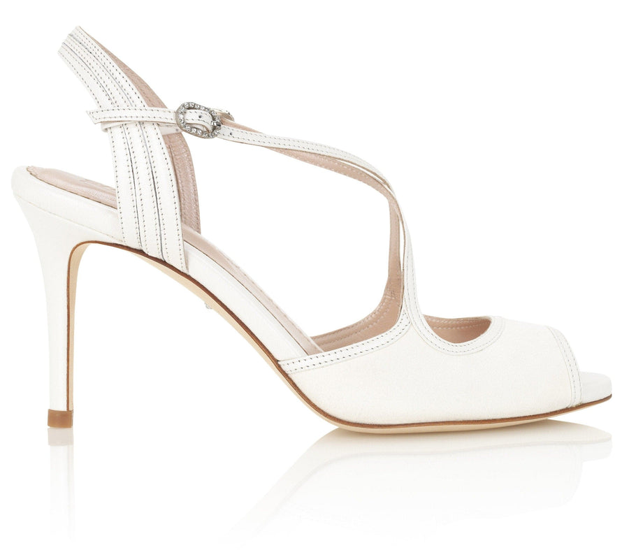 White slingback heels with a peep toe design, featuring crisscross straps and a decorative buckle on the ankle strap. The heel height is approximately 4 inches. The shoes are set against a clean, white background, showcasing their elegant silhouette from a side angle. image