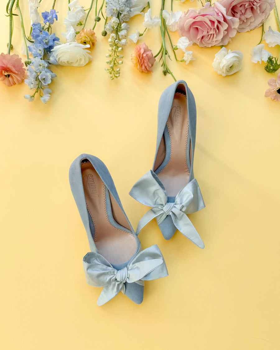 Pair of light blue high heels with bows on a yellow background with flowers. image