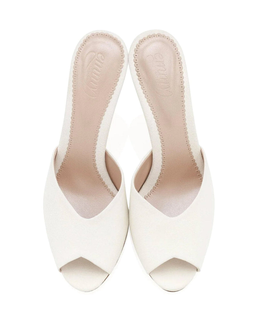 Open-toe white mules with a sleek design, featuring a smooth upper and a comfortable footbed. The shoes are displayed from a top-down angle against a plain white background, highlighting their minimalist style. image