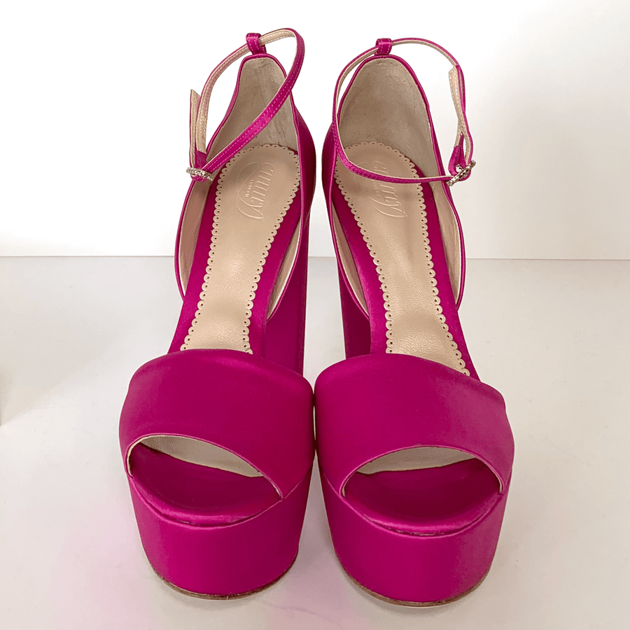 Fuchsia platform heels with an open toe design and a delicate ankle strap. The shoes feature a smooth satin finish and are positioned against a clean white background, showcasing their vibrant color and elegant silhouette. image