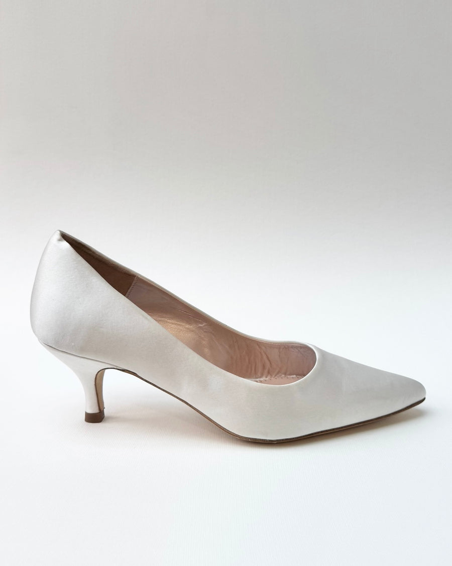 Elegant silver heels with a pointed toe and a modest kitten heel. The shoe is displayed against a neutral background, showcasing its sleek design and smooth finish. image