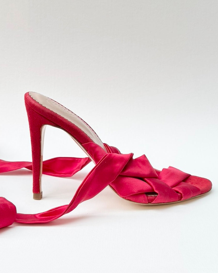 Pink high-heeled shoe with a pointed toe and intricate knot detailing on the front. The heel is approximately 4 inches tall. The shoe is displayed against a plain white background, showcasing its elegant design. image