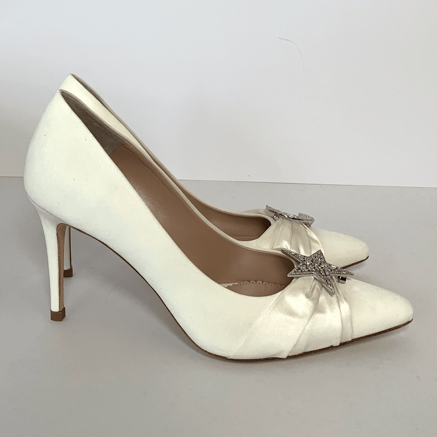 Elegant white heels featuring a satin finish with a decorative star embellishment on the toe. The shoes are positioned side by side against a plain white background, showcasing their sleek silhouette and pointed toe design. The heels are approximately 3 inches high. image