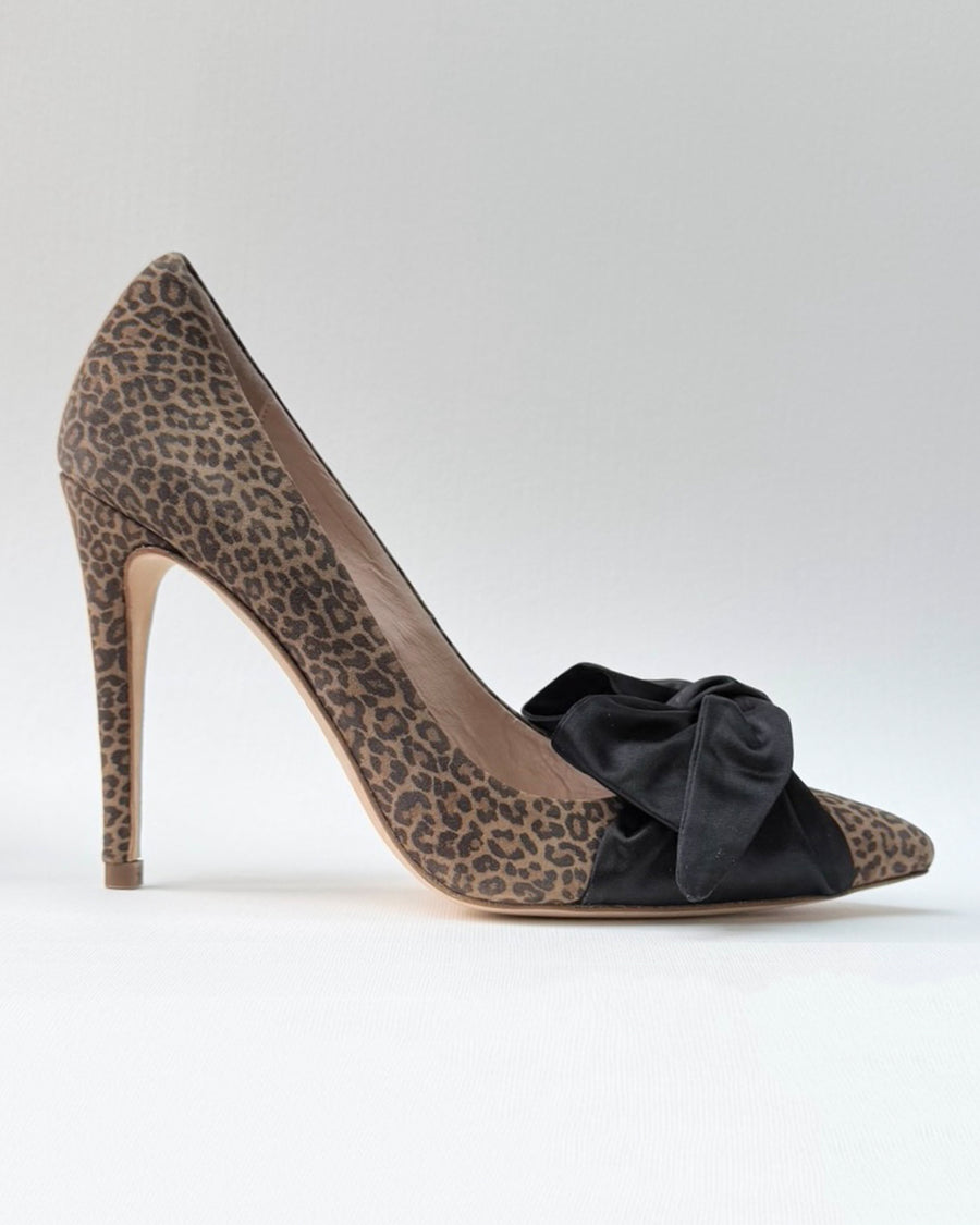 Leopard print high heel shoe featuring a black satin bow on the front. The shoe has a sleek silhouette and a stiletto heel, positioned against a plain white background for a clean presentation. image