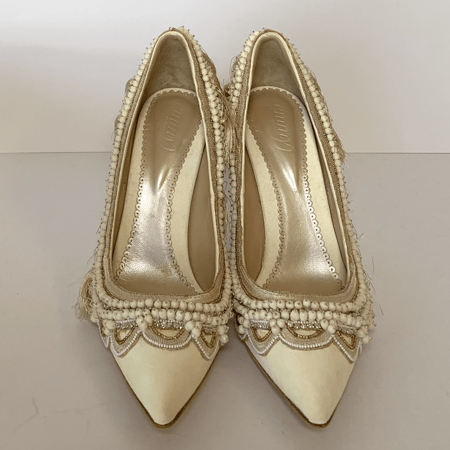 Elegant ivory heels adorned with intricate beading and fringe detailing. The shoes feature a pointed toe design and a smooth interior lining. The image is taken from a top-down angle, showcasing the shoes against a plain white background. image