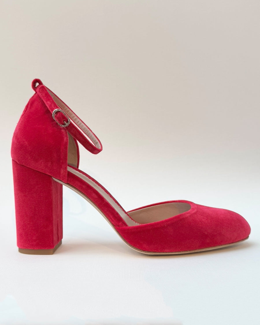 Red suede block heel shoes with a rounded toe and an ankle strap. The shoes are displayed against a plain white background, showcasing their vibrant color and texture. The heel height is approximately 3.5 inches. image