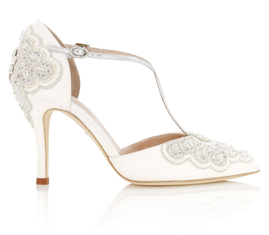Elegant white heels featuring intricate beaded embroidery on the upper. The shoes have a delicate ankle strap and a pointed toe design. The heel is high, providing a sophisticated silhouette. The image is taken against a clean, white background, showcasing the shoe from a side angle. image