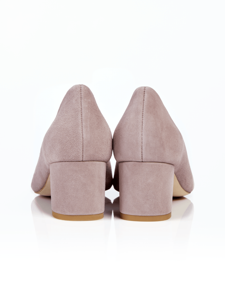 Block-heeled shoes in soft pink suede, featuring a rounded toe and a modest heel height of approximately 2.5 inches. The shoes are displayed against a clean white background, showcasing their smooth texture and elegant design. image